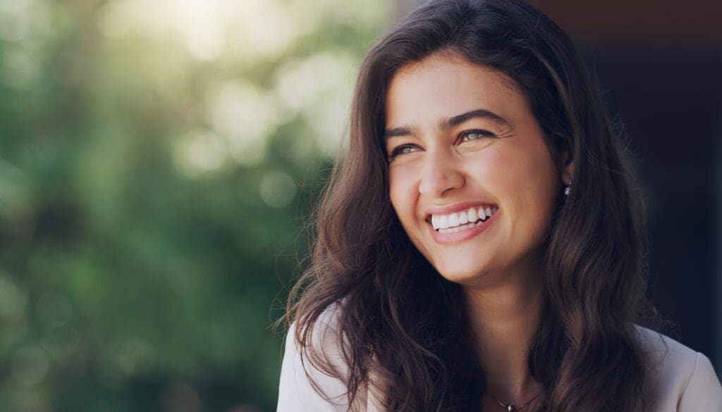 young woman smiling outdoors, perfect white teeth