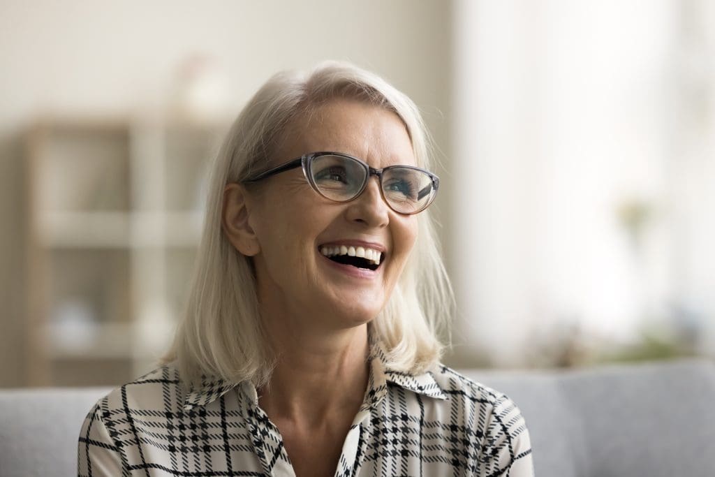 mature woman smiling on a couch, perfect smile, dental implants