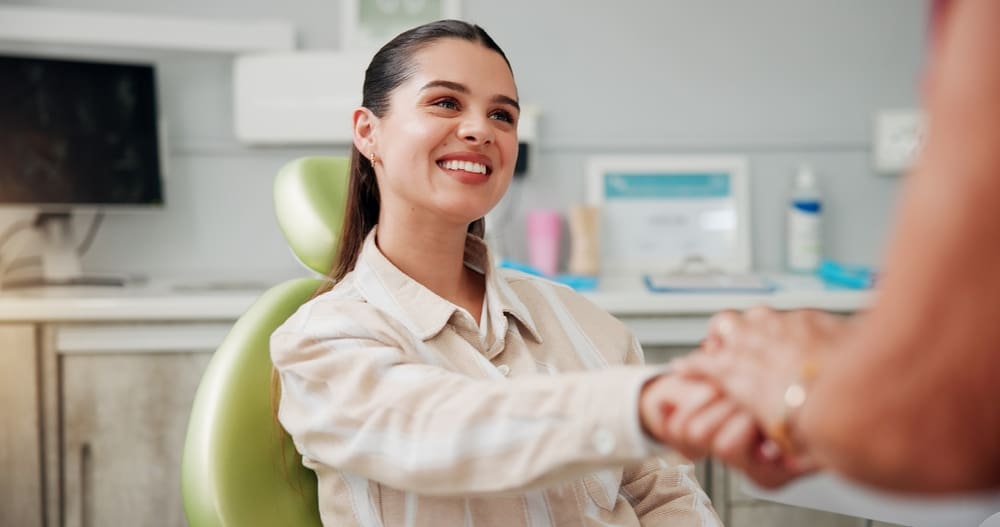 young woman shaking hands with dentist, modern dental office